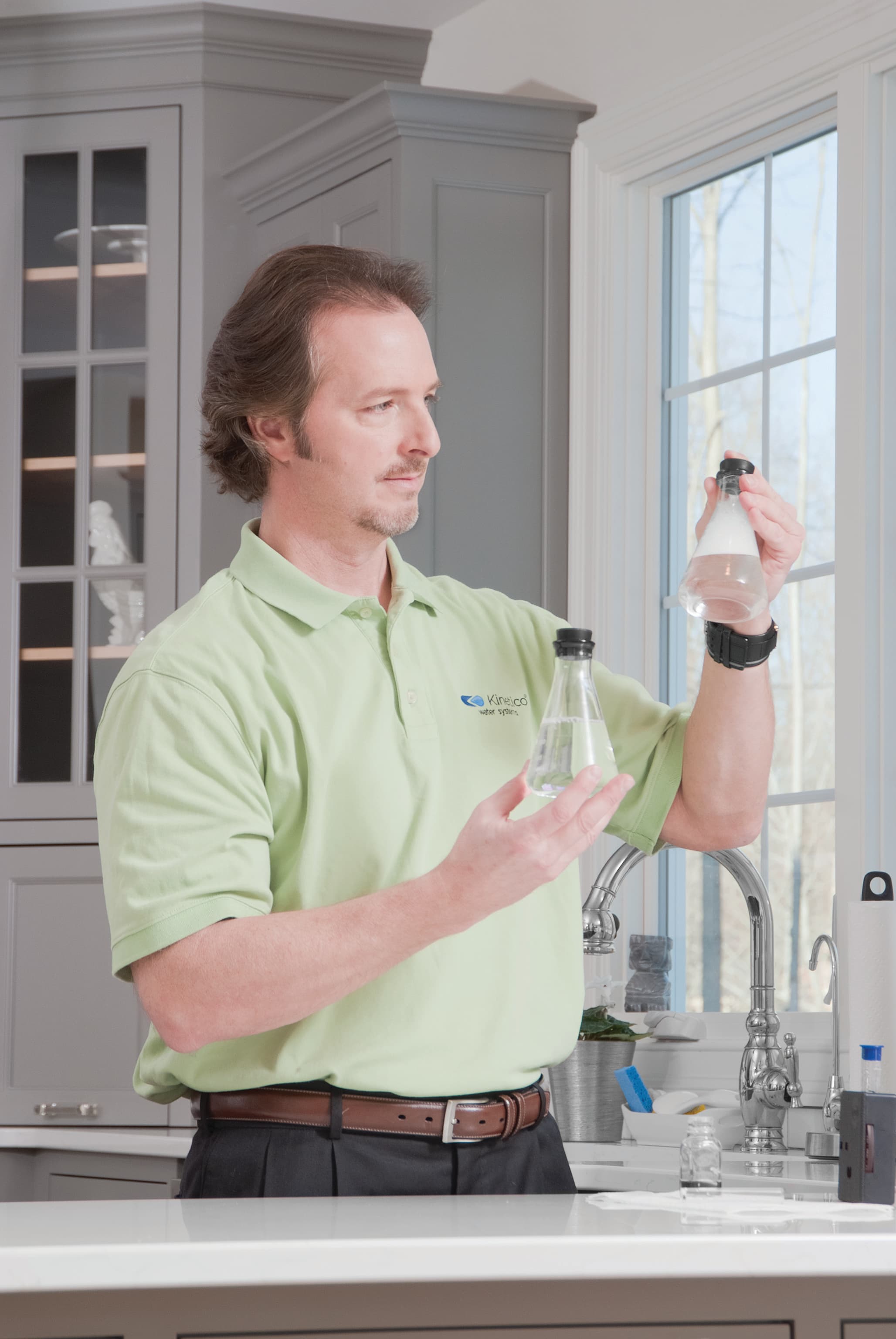 A Kinetico water professional comparing water samples in a kitchen
